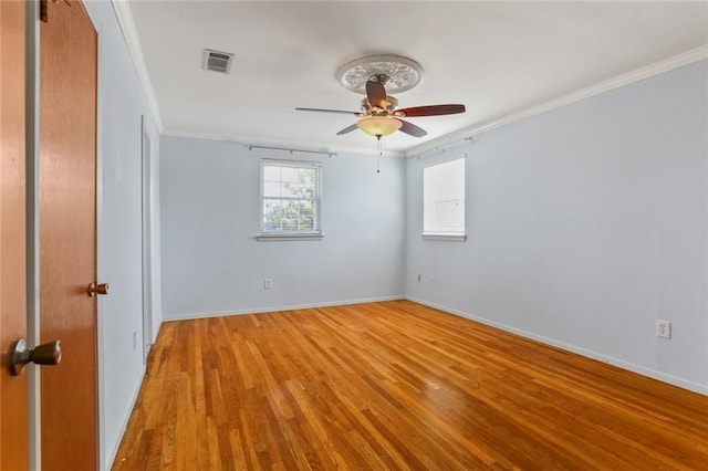 empty room with ceiling fan, visible vents, light wood-style floors, baseboards, and crown molding