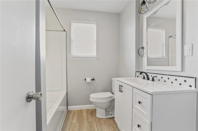 full bathroom featuring toilet, tub / shower combination, vanity, wood finished floors, and baseboards