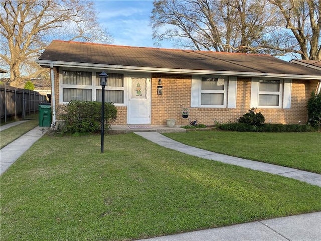 view of front of house featuring a front yard, brick siding, and fence