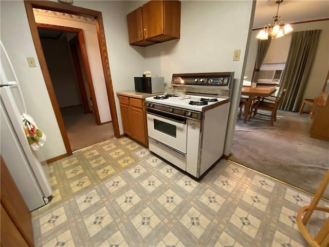 kitchen featuring white appliances, baseboards, brown cabinets, light countertops, and a notable chandelier