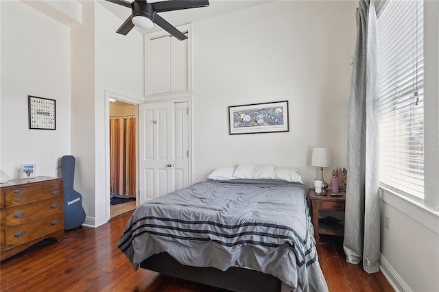 bedroom featuring a ceiling fan, a high ceiling, baseboards, and wood finished floors