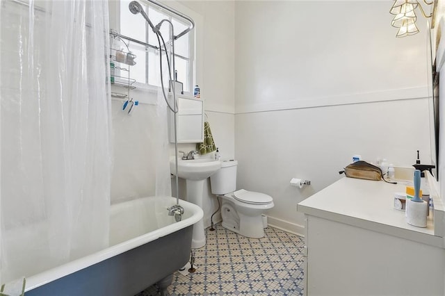 full bathroom featuring shower / bath combination with curtain, a sink, toilet, and baseboards