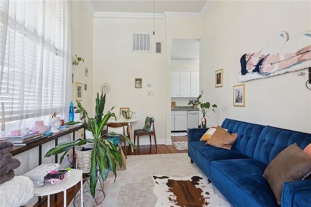 living room with wood finished floors, visible vents, and crown molding