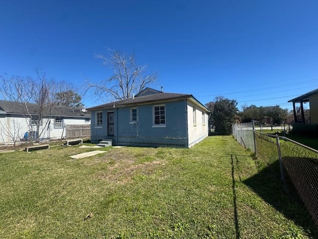 back of property with entry steps, a fenced backyard, a lawn, and stucco siding