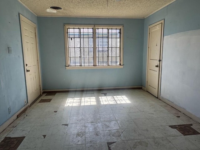 unfurnished room with visible vents, a textured ceiling, and baseboards