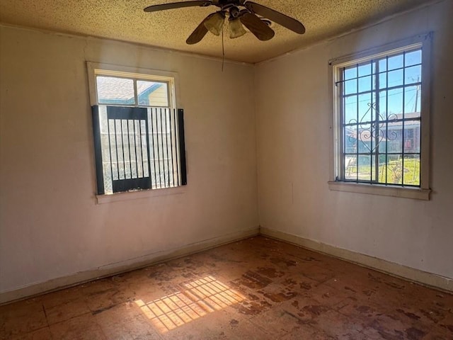 unfurnished room with a ceiling fan, baseboards, and a textured ceiling