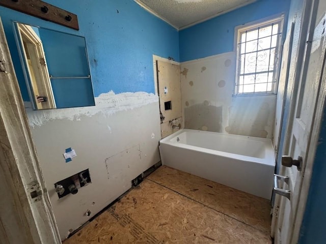 bathroom with a tub and a textured ceiling