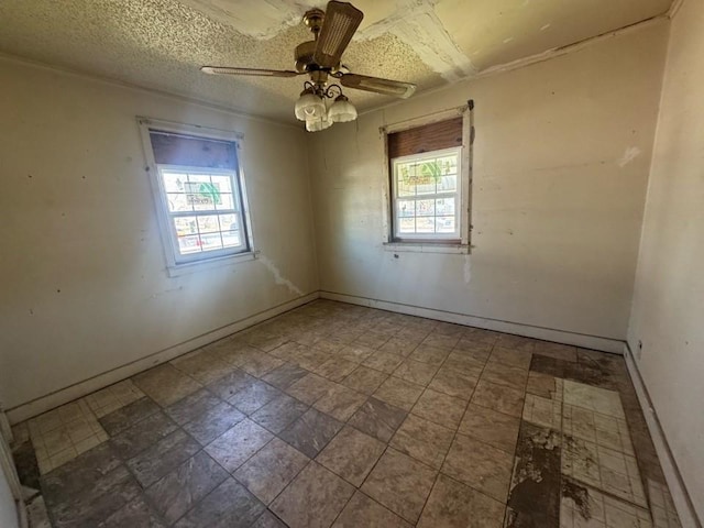 unfurnished room featuring plenty of natural light, baseboards, ceiling fan, and a textured ceiling