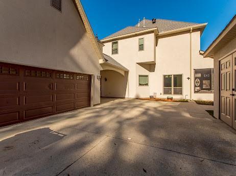 rear view of house featuring a garage, driveway, and stucco siding