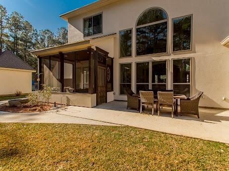 rear view of property with a patio, a sunroom, and stucco siding