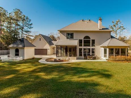 rear view of property featuring a lawn, a chimney, fence, an outdoor structure, and a patio area