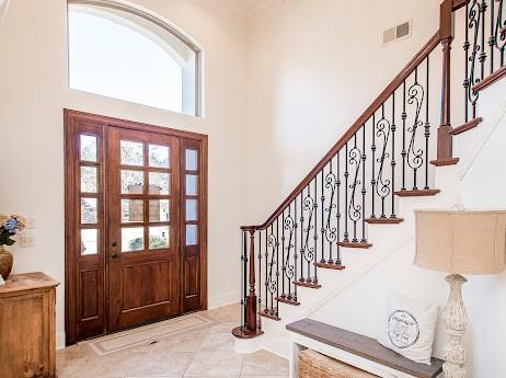 tiled entrance foyer featuring visible vents, a high ceiling, and stairs