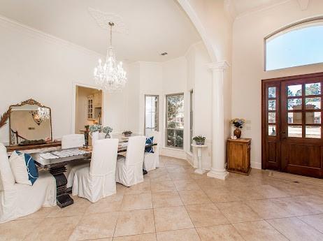 dining area featuring arched walkways, a notable chandelier, light tile patterned floors, ornamental molding, and ornate columns