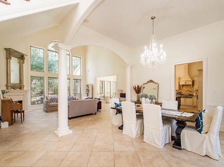 dining area with arched walkways, high vaulted ceiling, light tile patterned floors, beamed ceiling, and ornate columns