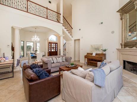 living area featuring arched walkways, a fireplace, ornate columns, and stairs