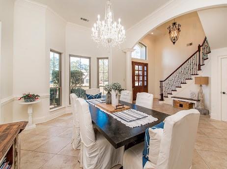 dining area featuring arched walkways, a notable chandelier, a high ceiling, ornamental molding, and stairway