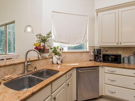 kitchen with a wealth of natural light, dishwasher, backsplash, black microwave, and a sink