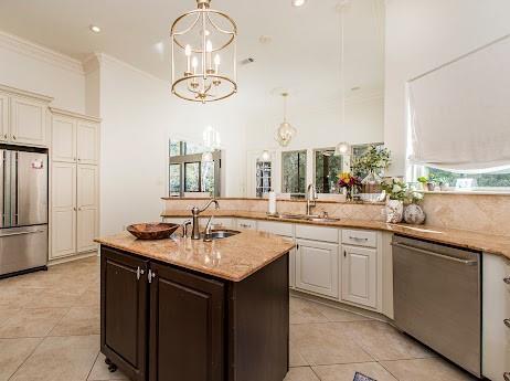 kitchen with light stone counters, ornamental molding, stainless steel appliances, and a sink