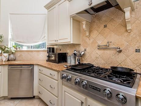 kitchen with appliances with stainless steel finishes, light stone countertops, decorative backsplash, and light tile patterned floors