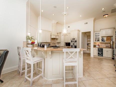 kitchen with decorative backsplash, ornamental molding, a kitchen breakfast bar, a peninsula, and premium range hood