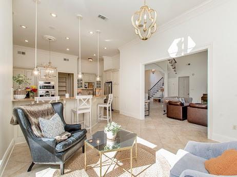 living area featuring light tile patterned floors, stairs, visible vents, and crown molding