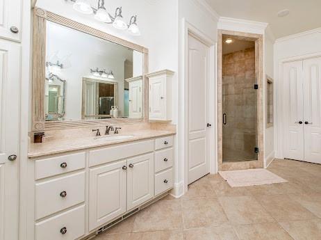 bathroom with ornamental molding, tile patterned flooring, a shower stall, and vanity