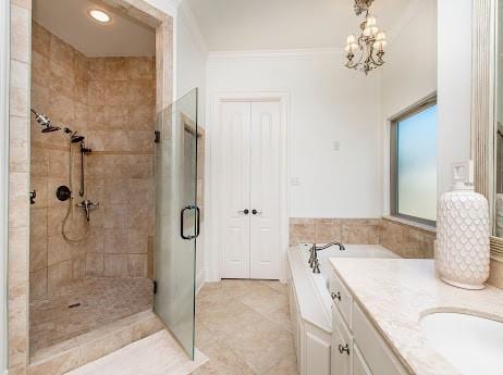 bathroom featuring a stall shower, ornamental molding, a garden tub, vanity, and a chandelier