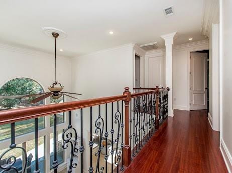 hall featuring a healthy amount of sunlight, visible vents, crown molding, and wood finished floors