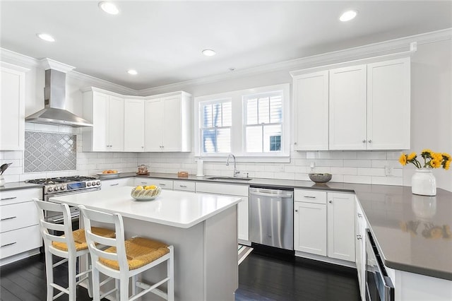 kitchen featuring stainless steel appliances, crown molding, a sink, and wall chimney exhaust hood