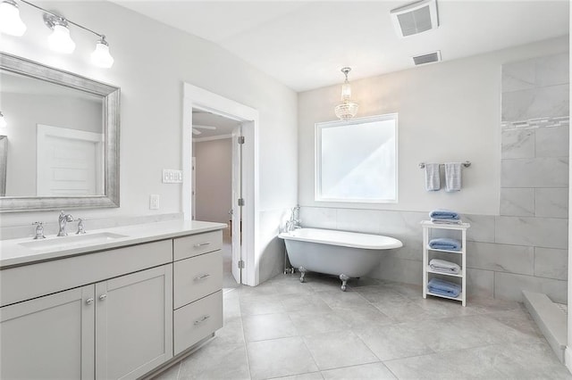 bathroom featuring tile walls, a soaking tub, visible vents, and vanity