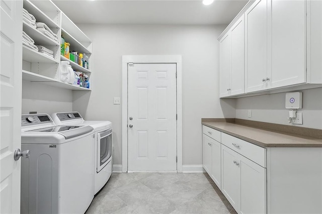 clothes washing area featuring washer and dryer, cabinet space, and baseboards