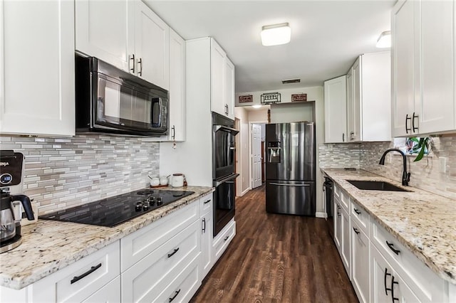 kitchen with dark wood-style floors, a sink, black appliances, white cabinetry, and backsplash