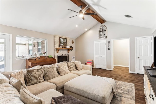 living room with visible vents, a ceiling fan, dark wood-style floors, vaulted ceiling with beams, and a brick fireplace