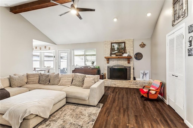 living room with beam ceiling, a ceiling fan, a brick fireplace, wood finished floors, and baseboards