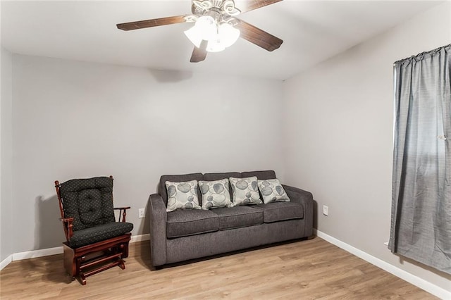 sitting room with a ceiling fan, light wood-style flooring, and baseboards