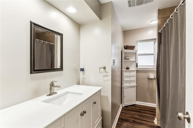 full bath with visible vents, vanity, baseboards, and wood finished floors