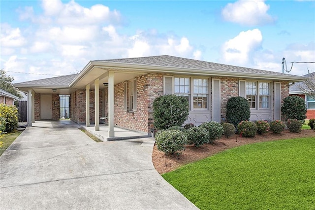 single story home featuring driveway, a shingled roof, a front lawn, a carport, and brick siding