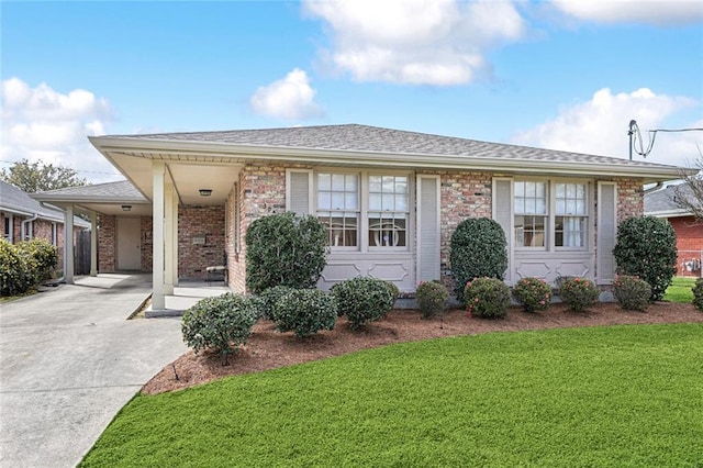 single story home with concrete driveway, an attached carport, a front lawn, and brick siding