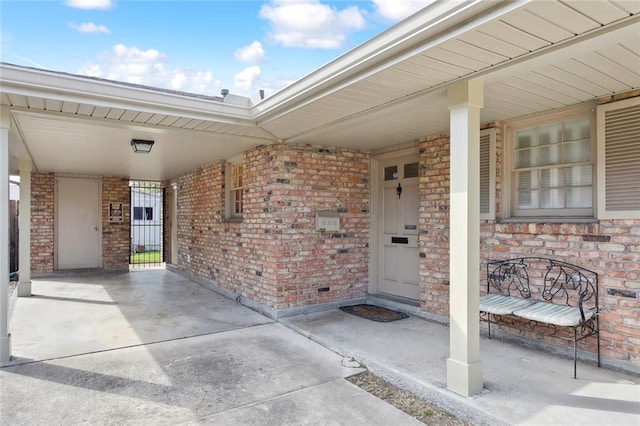 view of exterior entry featuring covered porch and brick siding