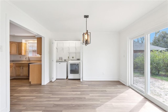 unfurnished dining area with light wood-style floors, a chandelier, a wealth of natural light, and independent washer and dryer