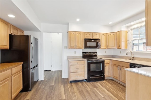 kitchen featuring light brown cabinets, a sink, light wood-style flooring, and black appliances