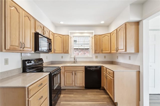 kitchen featuring light brown cabinets, black appliances, a sink, and light wood-style flooring