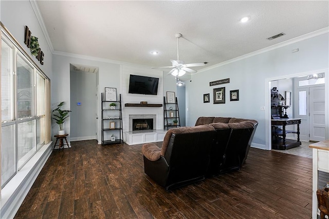 living room with a large fireplace, wood finished floors, visible vents, baseboards, and ornamental molding