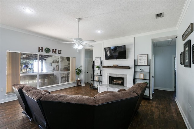 living area with visible vents, attic access, ornamental molding, a large fireplace, and wood finished floors