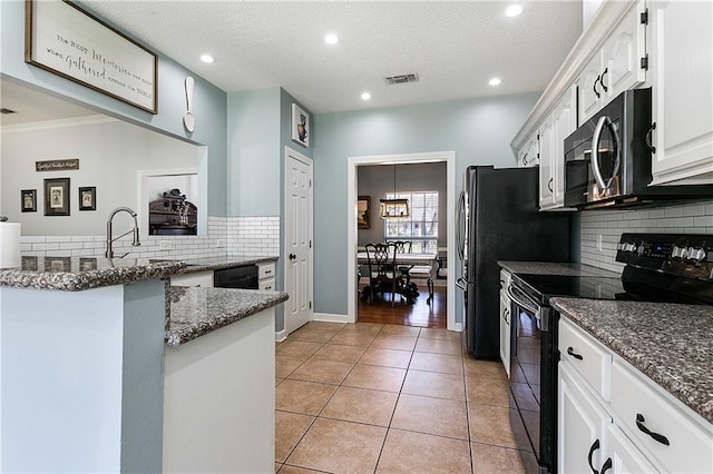 kitchen featuring light tile patterned floors, visible vents, white cabinetry, dark stone counters, and black appliances