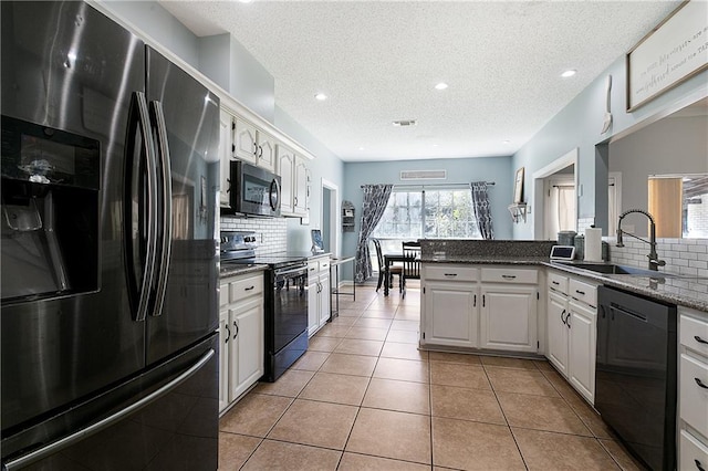 kitchen featuring black appliances, white cabinets, a sink, and light tile patterned flooring