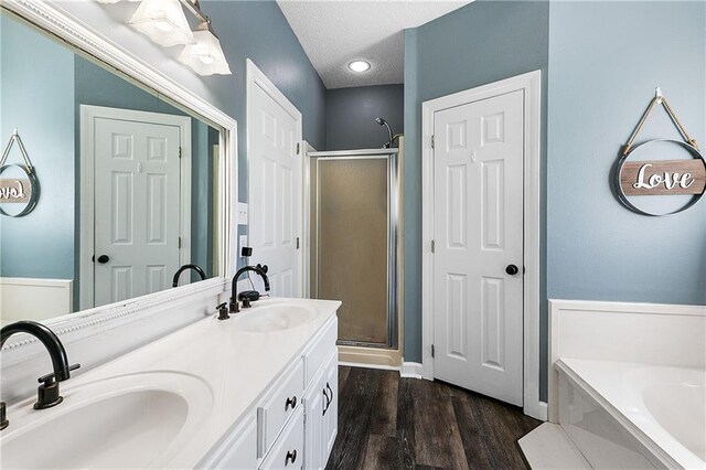 bathroom with wood finished floors, a stall shower, a sink, and a bath