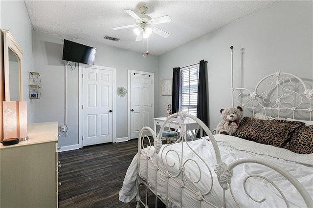 bedroom with a textured ceiling, visible vents, baseboards, a ceiling fan, and dark wood-style floors