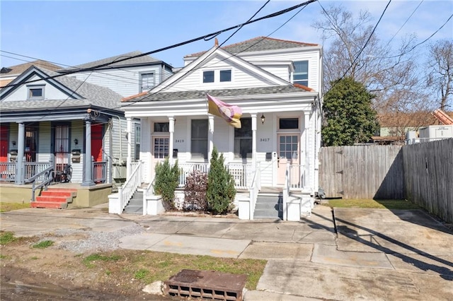 view of front of property with covered porch, fence, and roof with shingles