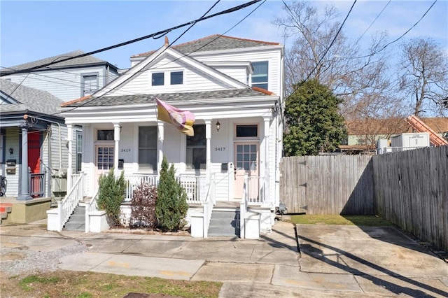 view of front of house with a porch, roof with shingles, and fence